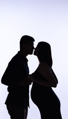 The silhouette of pregnant woman and her husband,holding hand together,with love and care