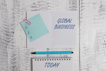 Word writing text Global Business. Business photo showcasing Trade and business system a company doing across the world Open squared spiral notepad clip note highlighter lying old wooden background