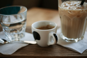 Coffee break concept. Morning habits. A cup of espresso and a glass of ice latte on a brown wooden table.