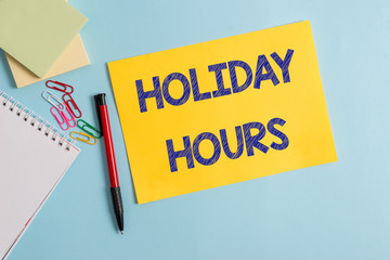 Writing note showing Holiday Hours. Business concept for employee receives twice their normal pay for all hours Plain cardboard and writing equipment placed on pastel colour backdrop