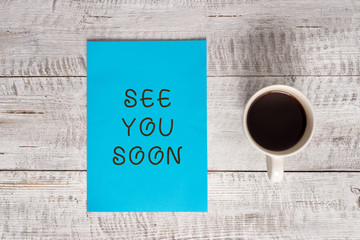 Conceptual hand writing showing See You Soon. Concept meaning used for saying goodbye to someone and going to meet again soon Stationary placed next to a coffee cup above wooden table