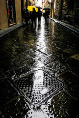 Tourists with umbrellas in the rainy medieval street in the center of Florence, Tuscany, Italy....