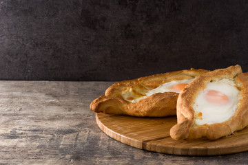 Traditional Adjarian Georgian khachapuri with cheese and egg on wooden table. Copyspace