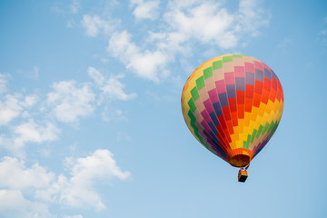 Fototapeta premium Colorful hot air balloon moving up in blue sky.