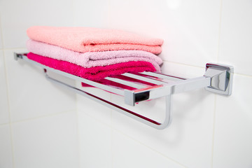 A stack of multi-colored towels on a metal shelf. Horizontally.
