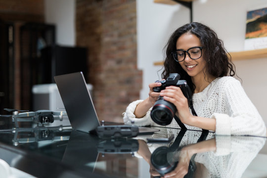 Young pretty woman photographer processing pictures sitting on the desk