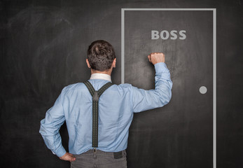 Business man knock by fist on boss door blackboard