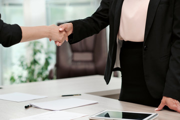 Two beautiful young women in business suits shake hands and smile. Hiring a job. Signing the agreement. Women at work.