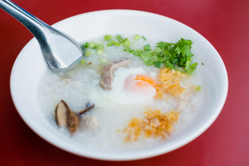 rice porridge, rice gruel or congee with pork, egg, sliced ginger and vegetable
