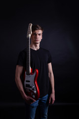 Young caucasian adult holding guitar in the studio