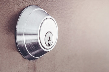 Modern new metallic grey shiny keyhole on door background. Side view of keyway with sun light and copyspace.