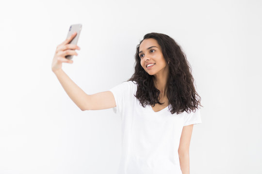Beautiful woman taking self picture with smartphone camera isolated on white