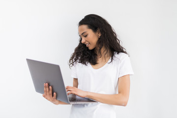 Naklejka premium Young smiling woman in casual clothes holding laptop and sending email to her best friend
