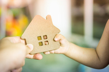 Baby Hands holding a house model with mother hand. The concept of relocation, mortgage,...