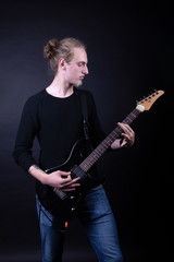 Young caucasian adult playing guitar in the studio