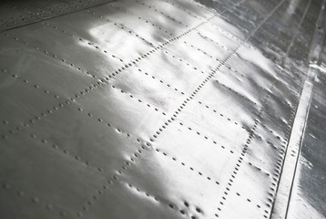 The texture of the surface of the aluminum wing of the aircraft with rivets. Selective focus.