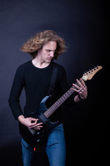 Young caucasian adult playing guitar in the studio