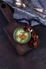 Broccoli soup served in rustic mug on a kitchen cutting board.