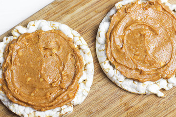 crunchy natural peanut butter sandwich with rice cake bread and knife with peanut butter on plate. Proper nutrition diet vegetarian breakfast