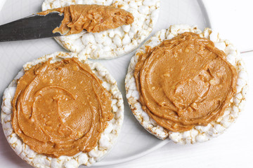 crunchy natural peanut butter sandwich with rice cake bread and knife with peanut butter on plate. Proper nutrition diet vegetarian breakfast