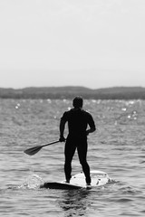 Fototapeta na wymiar Mann auf Surfbrett im See