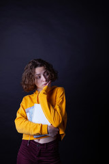 Young caucasian highschool girl in yellow hoodie posing in the studio