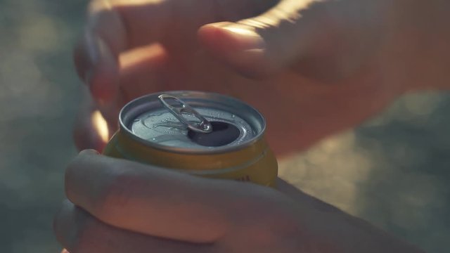 Opening misted wet can of beer sun backlight outdoors
