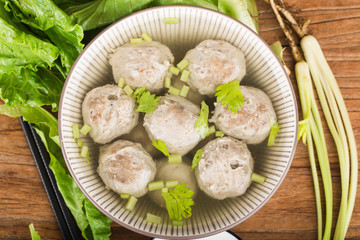 a bowl of beef ball soup on a wooden board background