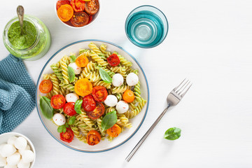 healthy fusilli pasta with pesto sauce, roasted tomatoes, mozzarella