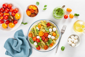 healthy fusilli pasta with pesto sauce, roasted tomatoes, mozzarella