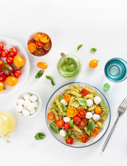 healthy fusilli pasta with pesto sauce, roasted tomatoes, mozzarella