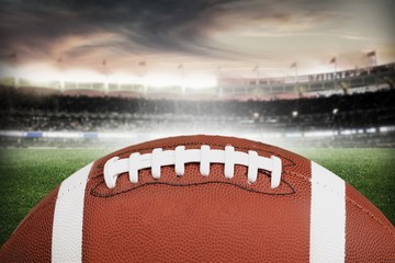 American football ball on stadium field background