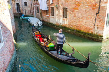 Fototapeta na wymiar Gondolier on gondola at the views of Venice background, Italy