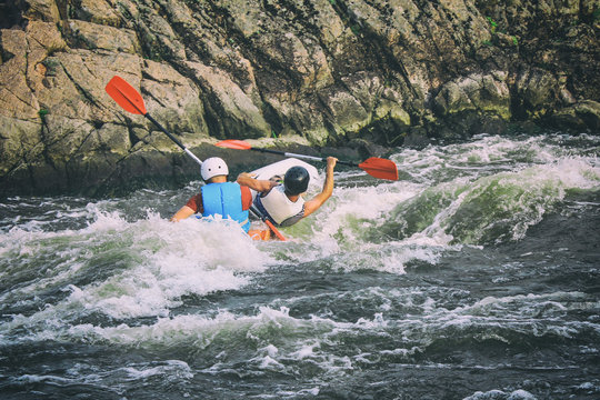 Kayakers fights the white water in a Pivdenny Bug river. They and their kayak are flipping over in the the wild water.