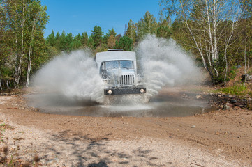 Obraz na płótnie Canvas the truck passes through a puddle