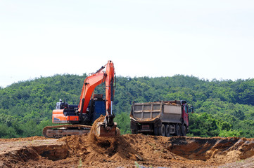 Excavator loading dumper truck on mining site 