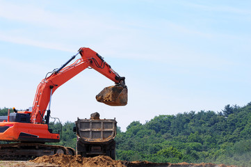 Fototapeta na wymiar Excavator loading dumper truck on mining site 