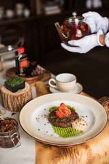 Grilled beef meat on msshed green peanut with burdock root puree. Servant pours tea.