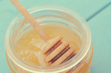 Honey and honey accessories for its use on a blue wooden background.