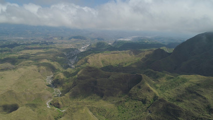 Aerial view of mountains covered with green vegetation, valley, trees in vicinity volcano Pinatubo. Slopes of mountains, sky and clouds. Cordillera region. Luzon, Philippines.