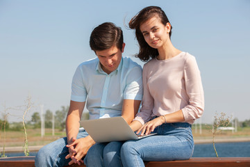 Couple using a laptop outdoors and looking happy