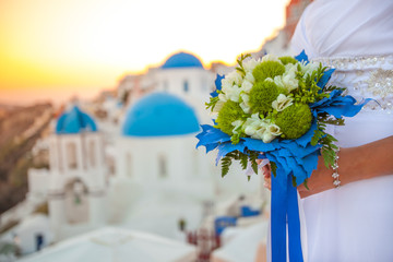 Bride holds wedding bouquet in white and green colors and blue decor against the backdrop of the...