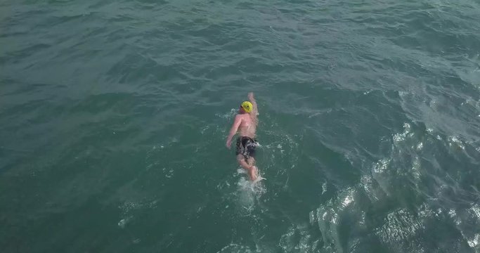 Top Down Aerial Drone View Of A Sea Swimmer Swimming And Training Towards His Goal In The Cold Atlantic Ocean In Cornwall UK