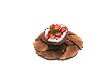 coconut cut with pieces of banana and strawberry with mint on a wooden carved stand
