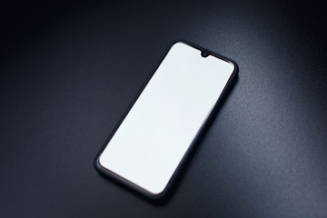 Modern black smart phone isolated on dark background in perspective view. New smartphone mockup with blank touch screen.