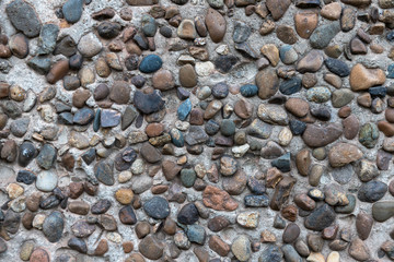 Concrete plaster interspersed with many smooth river stones. Decorative wall.