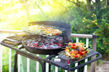 Assorted delicious grilled meat with vegetables over the coals on barbecue in green garden, summer party concept.