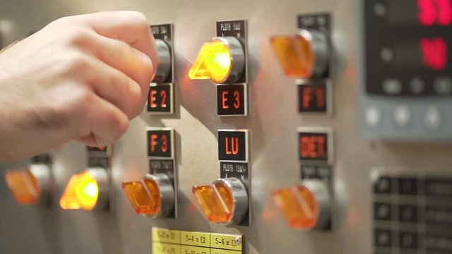 Worker's hands on factory switcher with buttons.