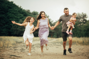 Happy family has fun, runs and laughs on a walk.