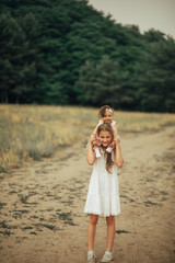 The girl carries her little sister on the shoulders.